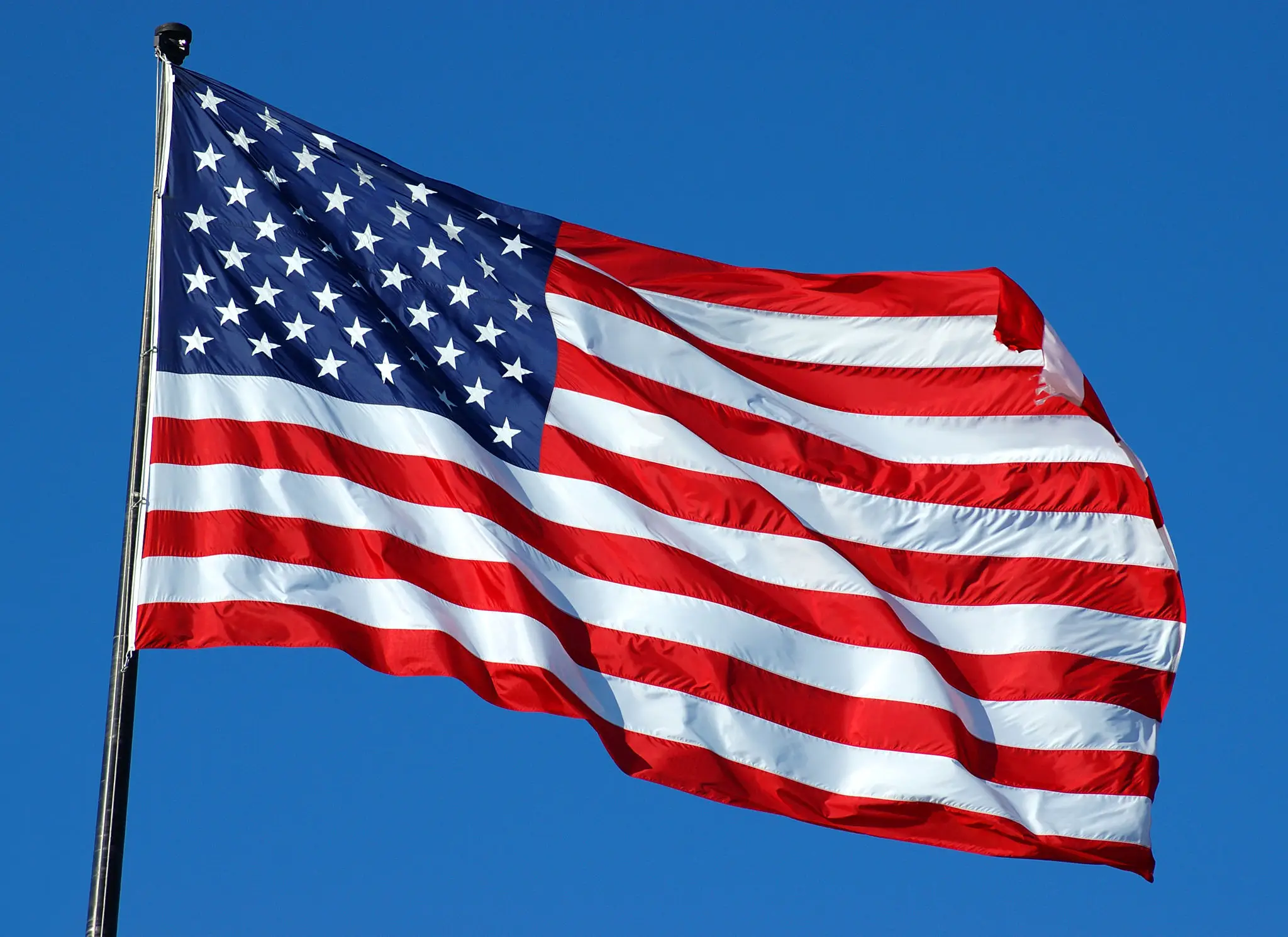 American flag waving against a clear blue sky.